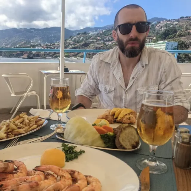bearded man in sunglasses eating seafood